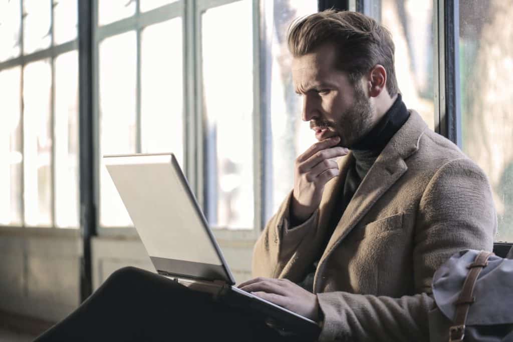 Man holding his chin while facing laptop